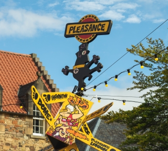 The Pleasance wayfinder pole in pleasance courtyard. It is yellow, with arms pointing in different directions.